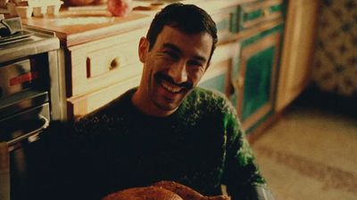 a man sitting in a kitchen holding a turkey