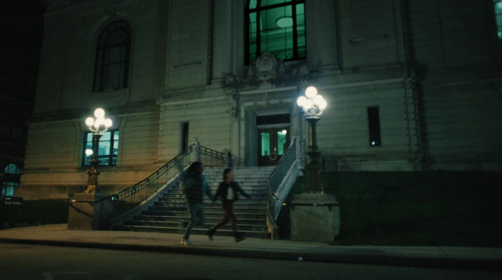 a couple of people walking down a street at night