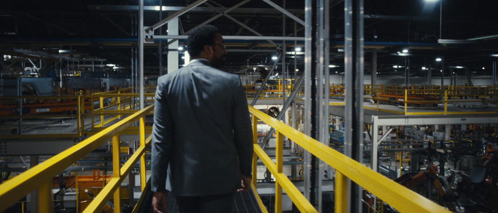 a man in a suit is standing in a factory