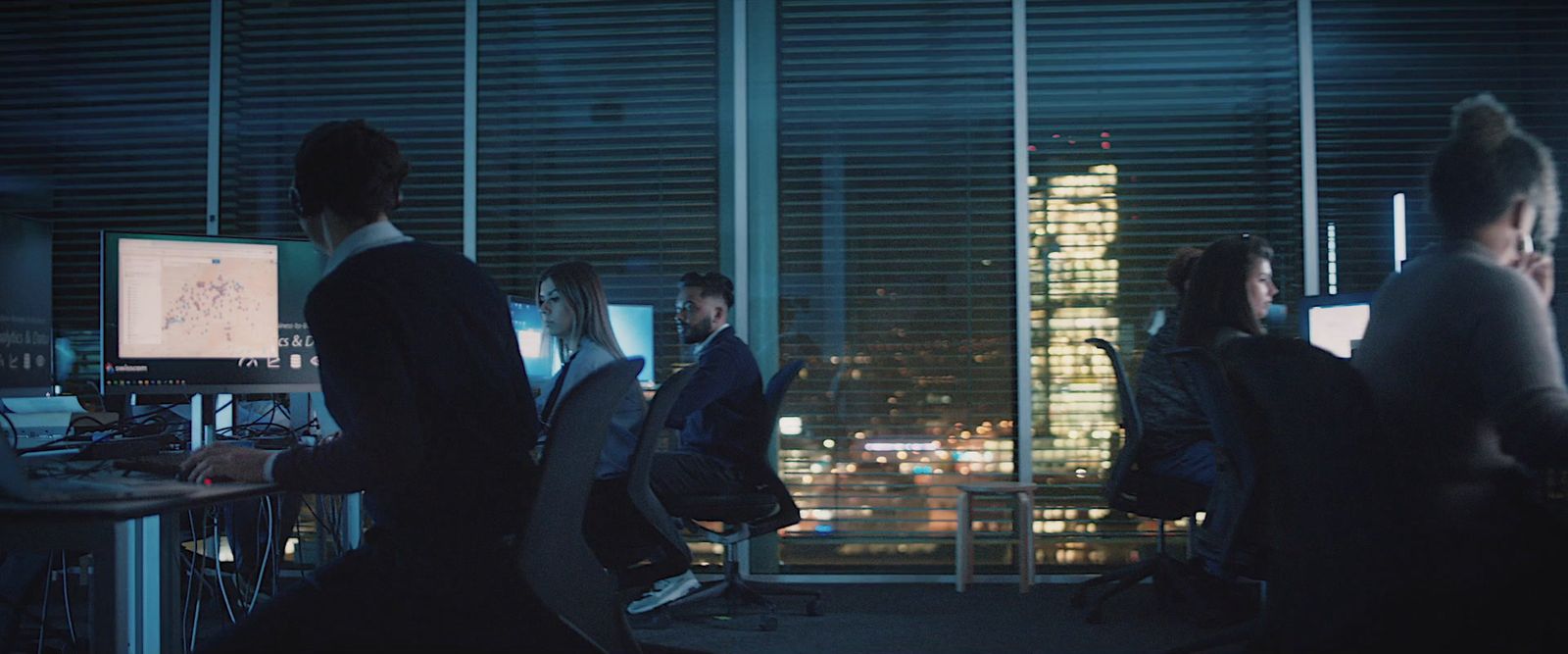 a group of people sitting at a desk in front of computer monitors