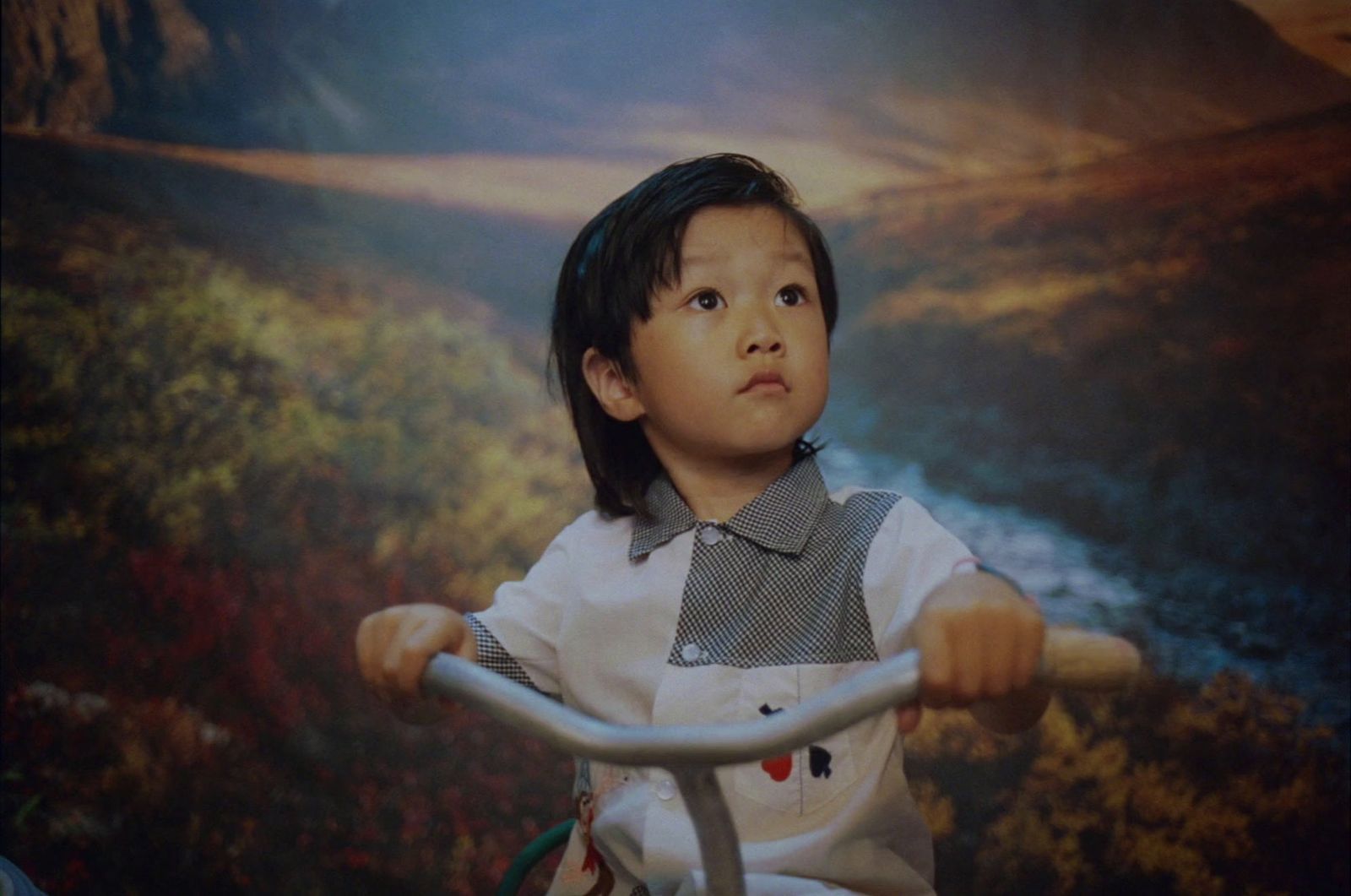 a young boy riding a bike in front of a painting