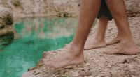 a person standing on a rock next to a body of water