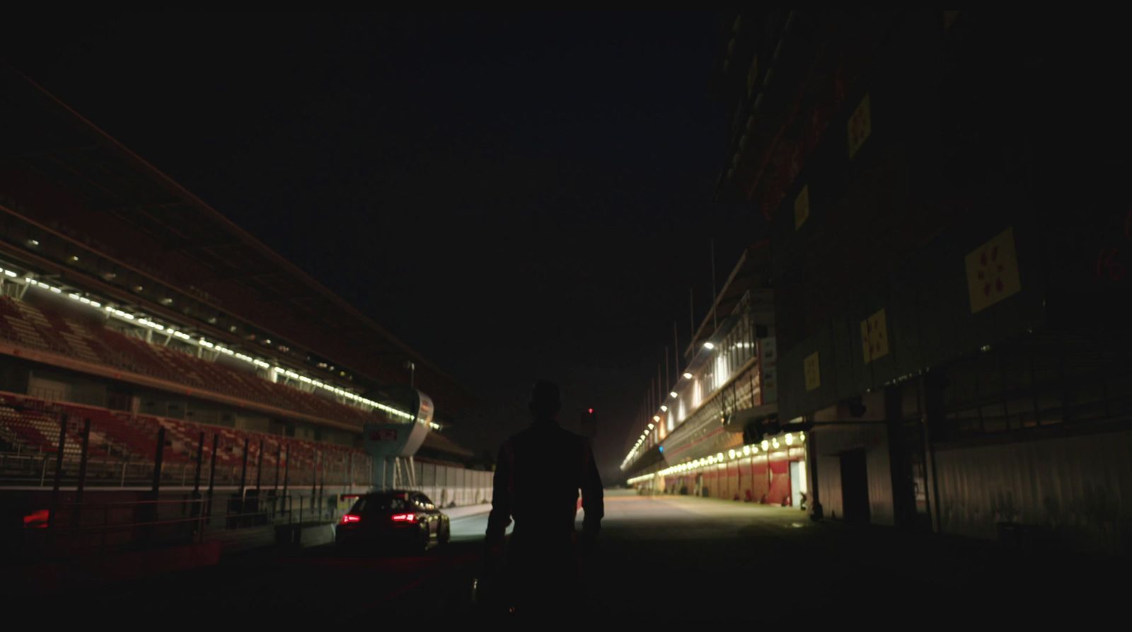 a man standing next to a parked car at night