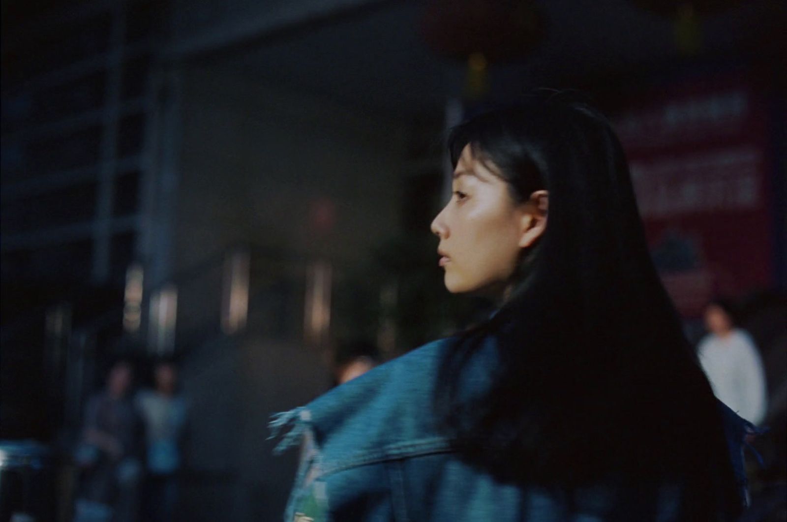 a woman with long black hair walking down a street