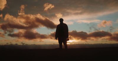 a silhouette of a person standing in front of a sunset