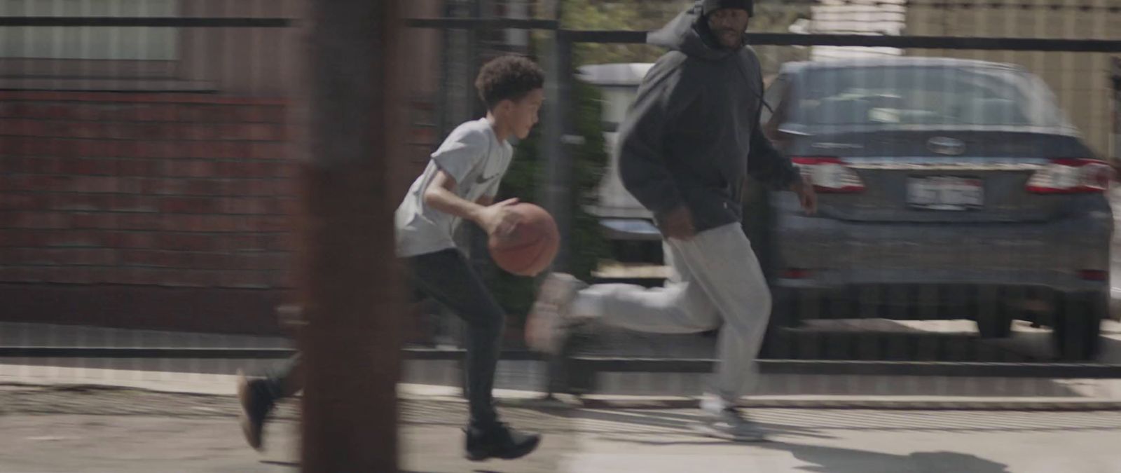 a young man dribbling a basketball past a young man