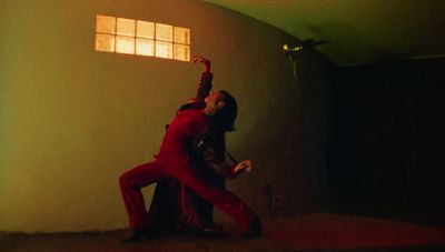 a man in a red suit dancing in a dark room