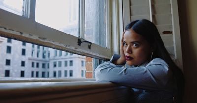 a woman leaning against a window sill looking out the window