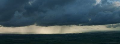 a large storm cloud looms over a rural area