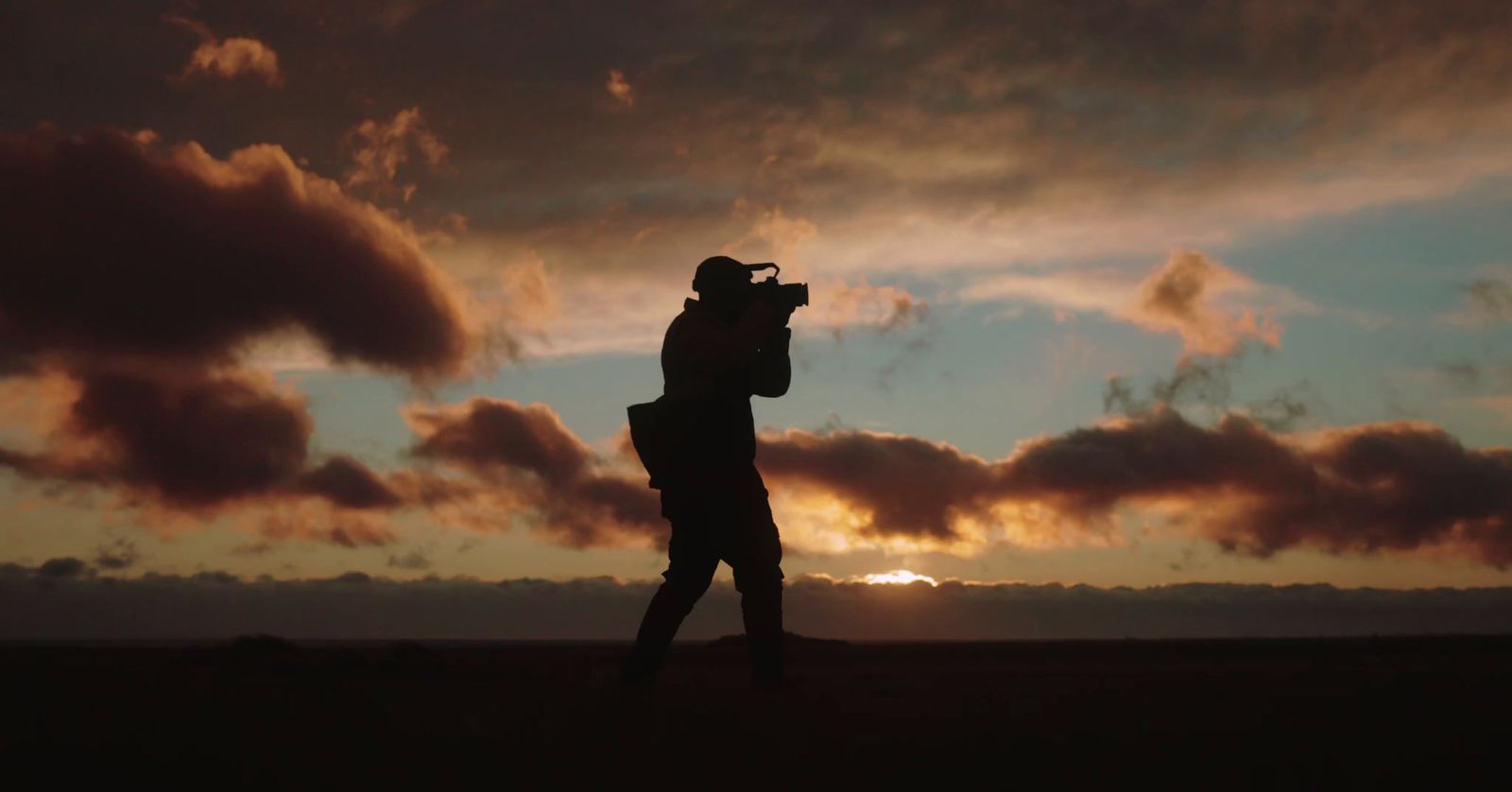 a person taking a picture with a camera at sunset