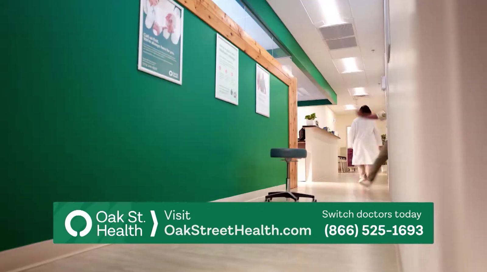 a man walking down a hallway next to a green wall