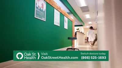 a man walking down a hallway next to a green wall