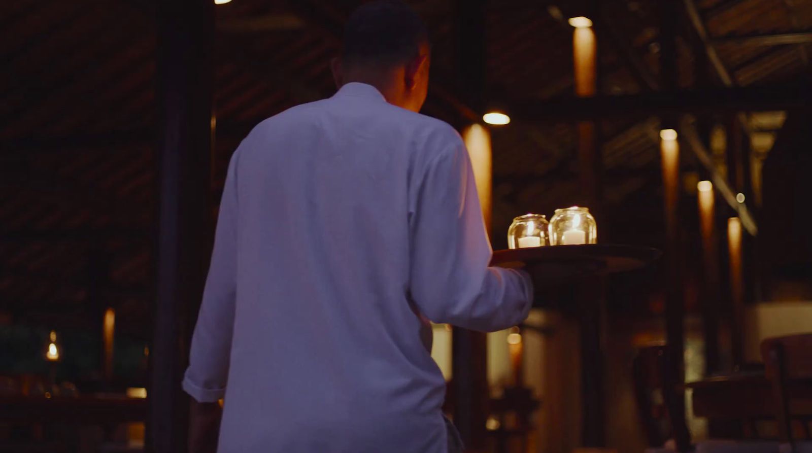 a man holding a tray with two jars on it