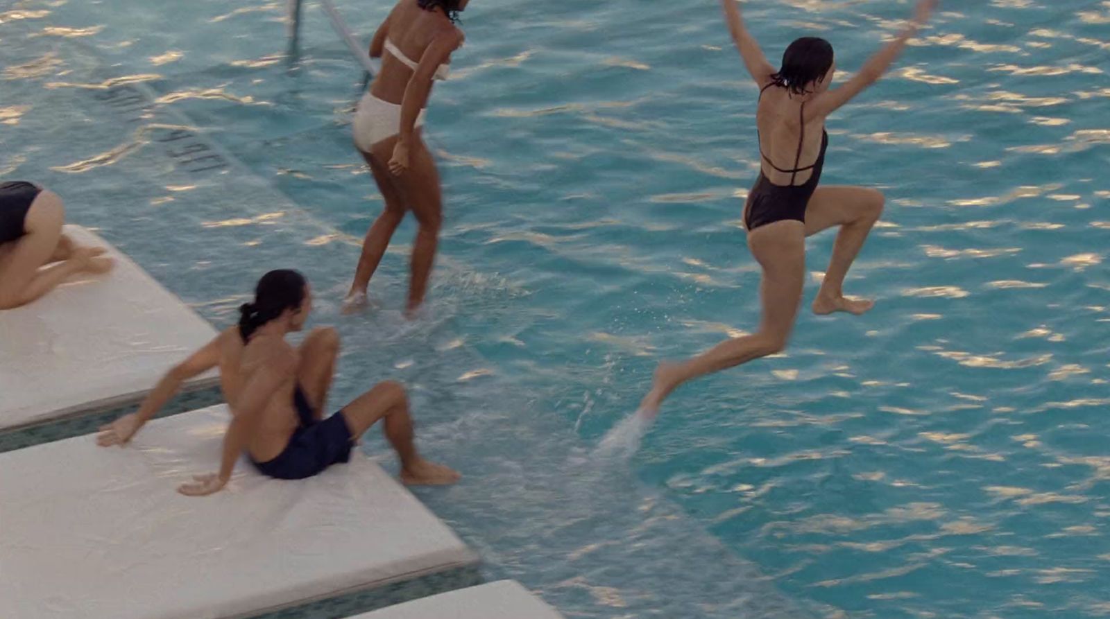 a group of women in bathing suits jumping into a swimming pool