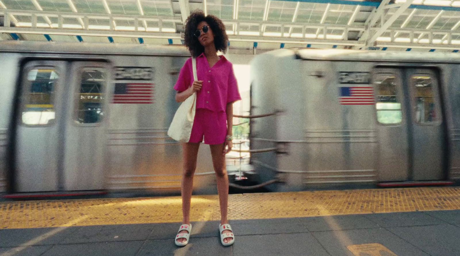 a woman in a pink shirt and shorts standing in front of a train