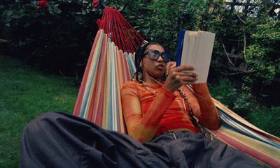 a woman laying in a hammock reading a book