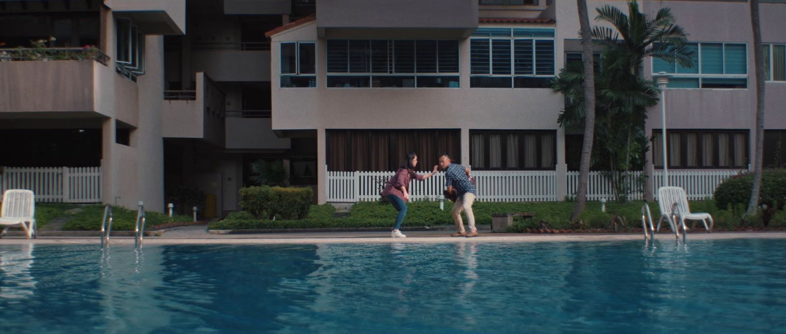 a couple of people standing next to a swimming pool