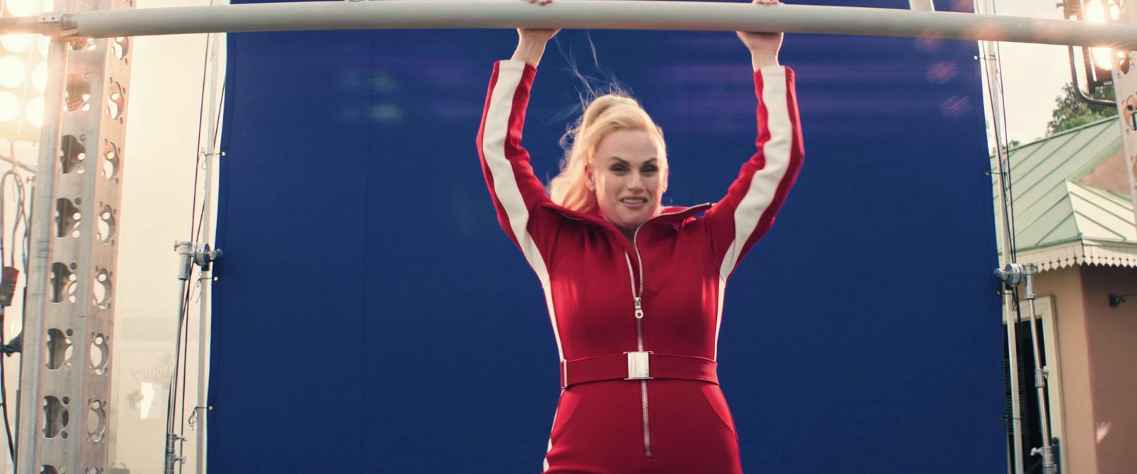 a woman in a red jumpsuit is holding a bar