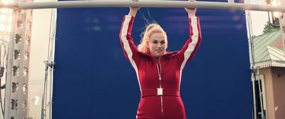 a woman in a red jumpsuit is holding a bar