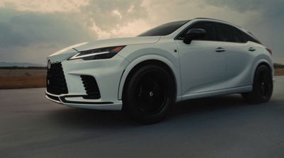 a white car driving down a road under a cloudy sky