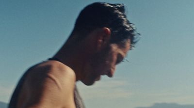 a man with no shirt on standing on a beach