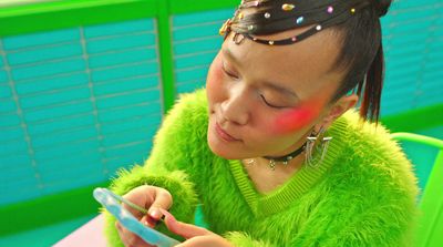 a woman in a green sweater looking at her cell phone