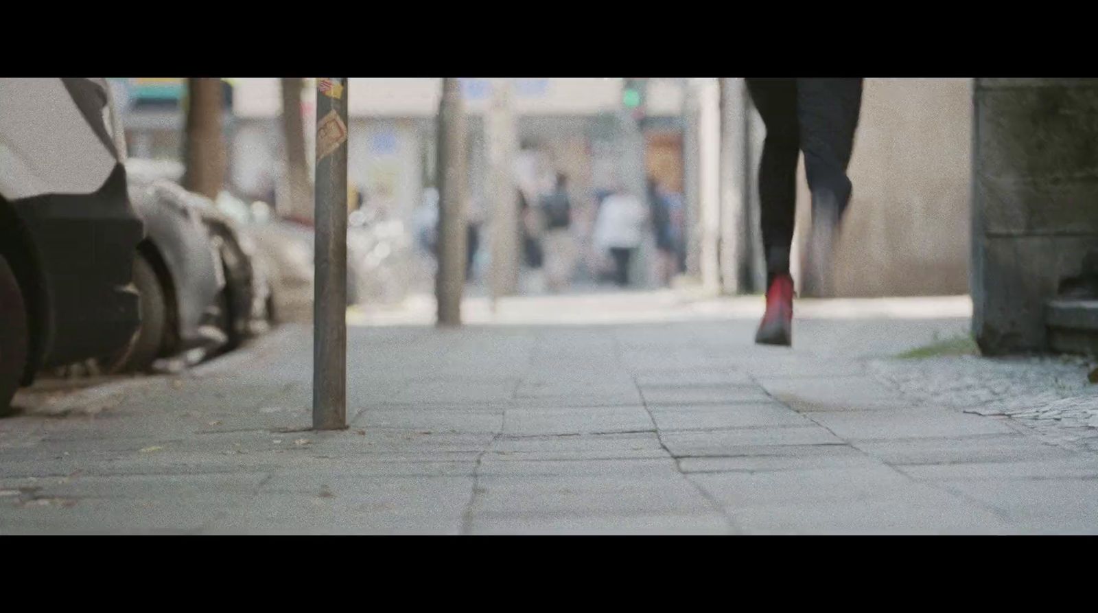 a person walking down a sidewalk next to parked cars