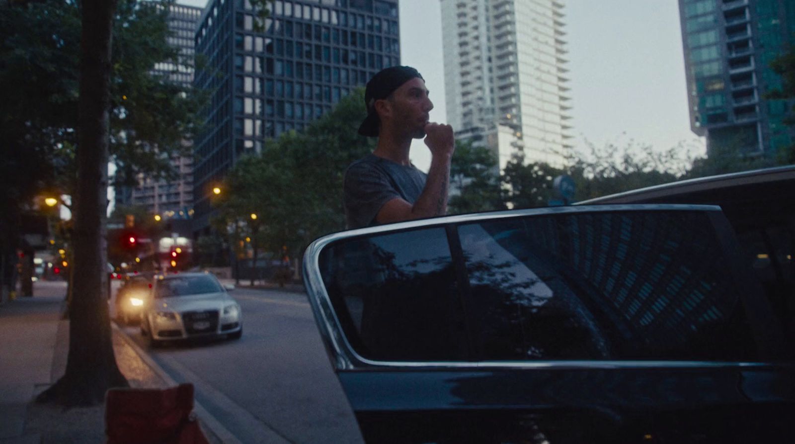 a man standing next to a car on a city street