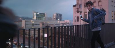 a man standing on a balcony looking at his cell phone