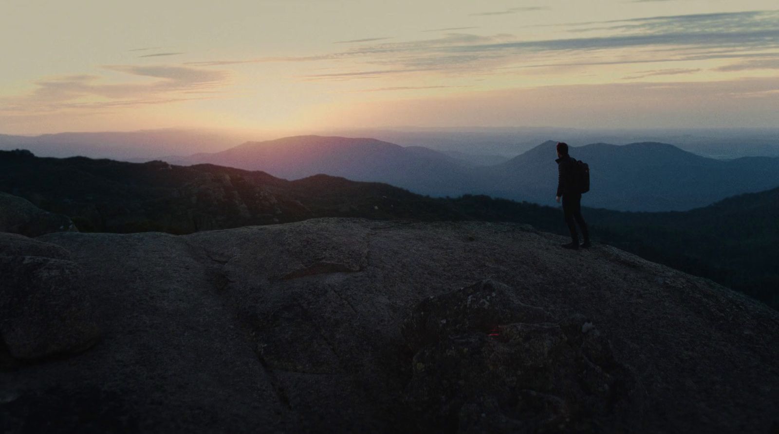 a man standing on top of a mountain at sunset