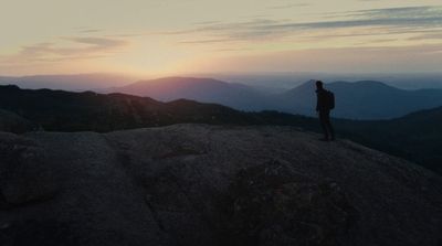 a man standing on top of a mountain at sunset