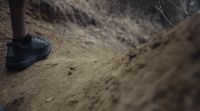 a person walking up a dirt hill in the woods