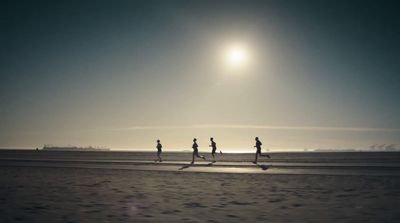 a group of people running on a beach