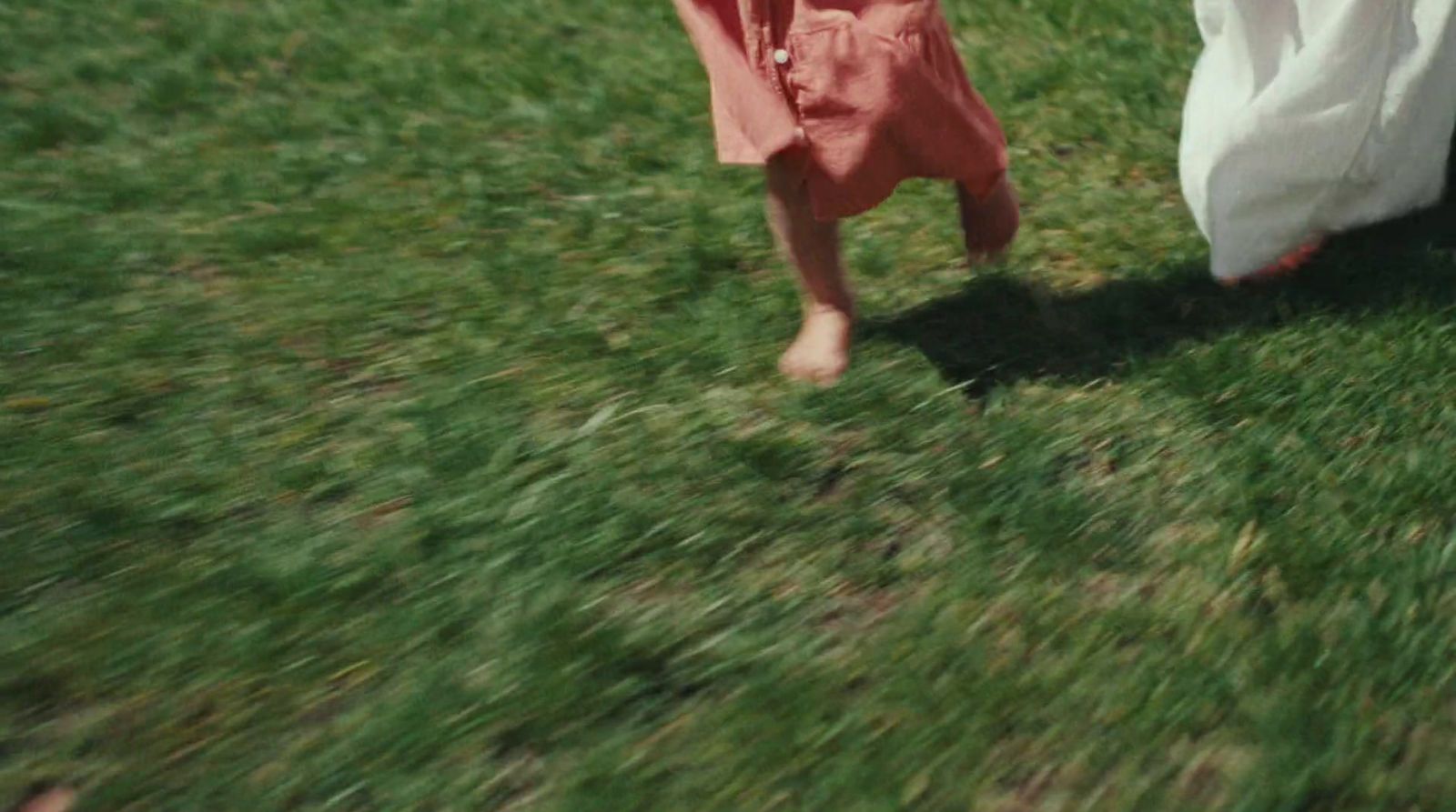 a little girl walking across a lush green field