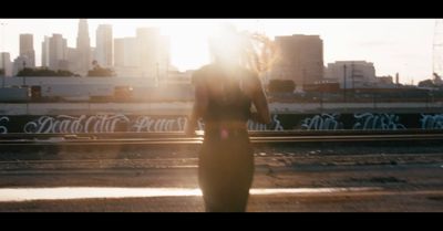 a woman walking down a train track with a city in the background