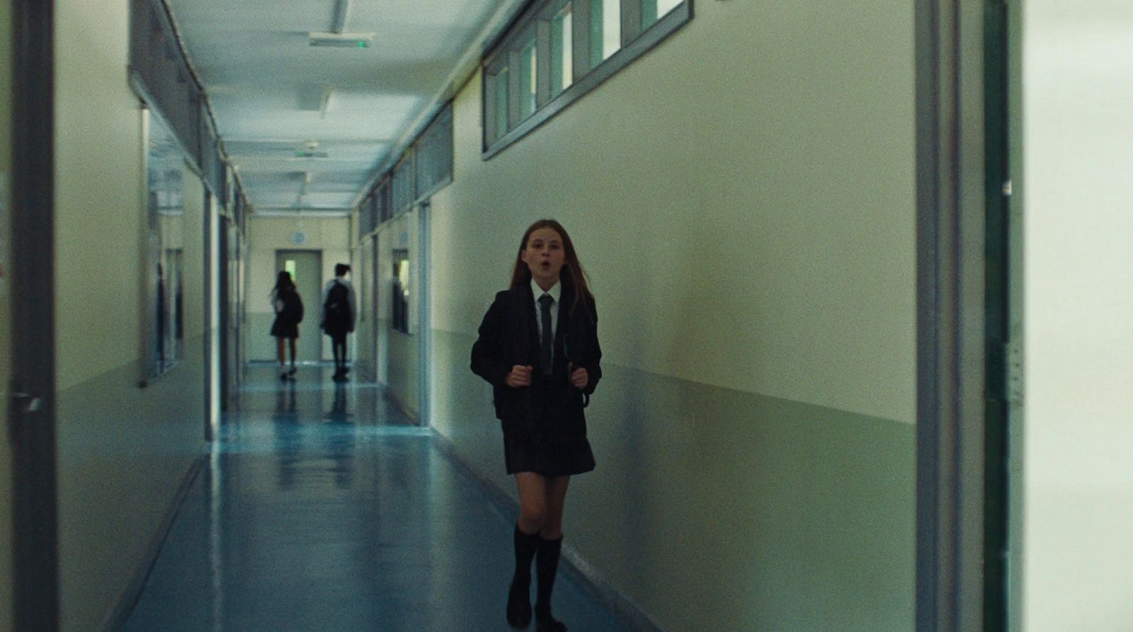 a woman in a suit and tie walking down a hallway