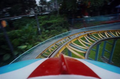 a close up of a roller coaster with trees in the background