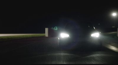 a couple of cars driving down a street at night