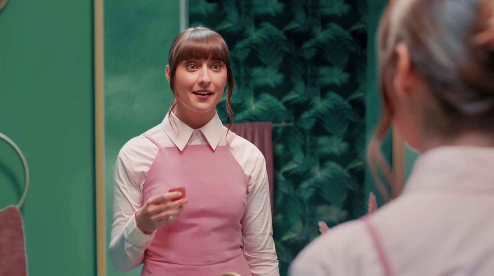 a woman in a pink apron standing in front of a mirror