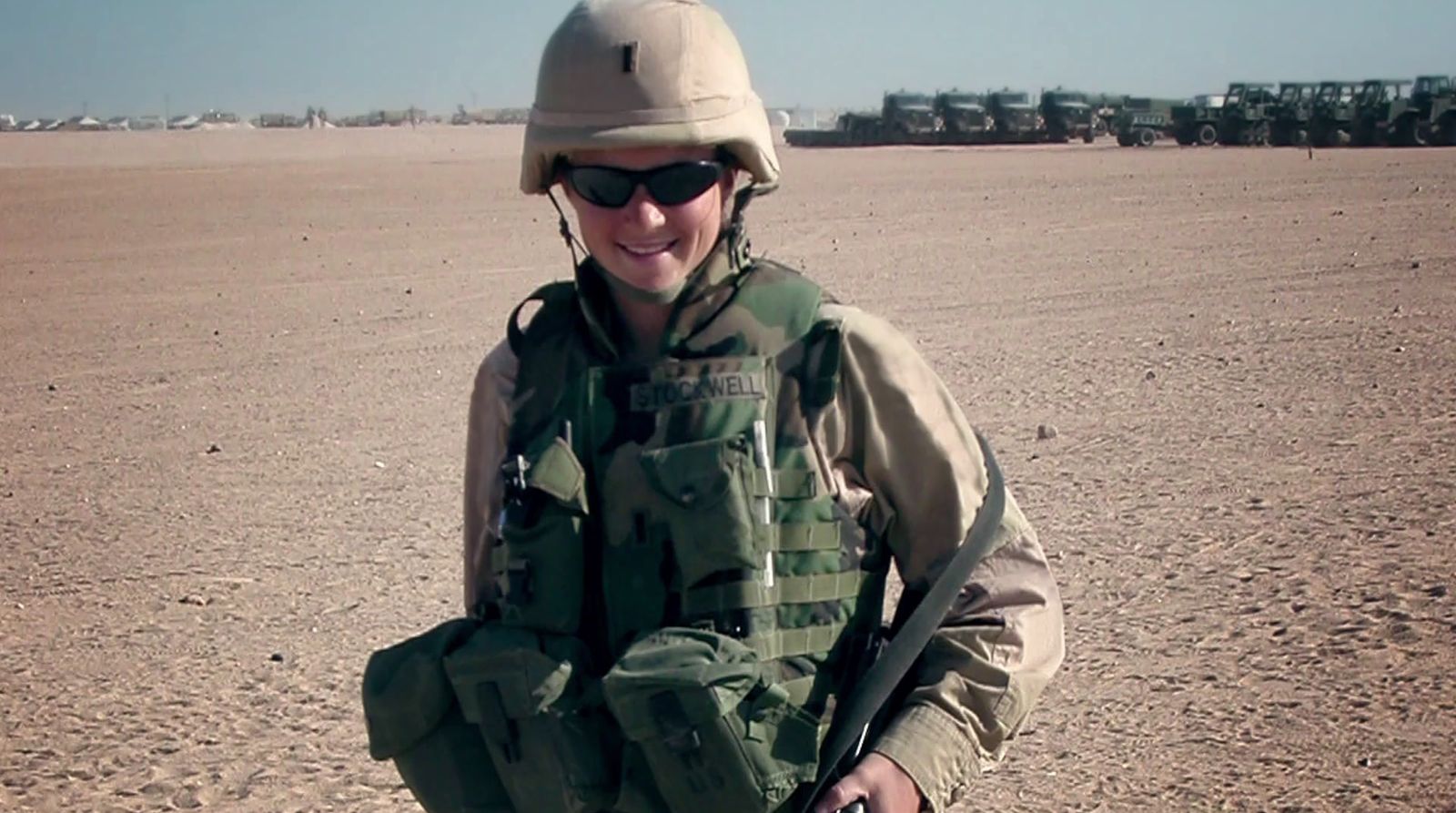 a woman in a military uniform is standing in the desert