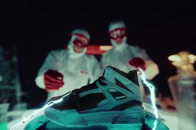 two people in white suits and red goggles standing next to a pair of sneakers