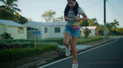 a girl is running down the street on a skateboard