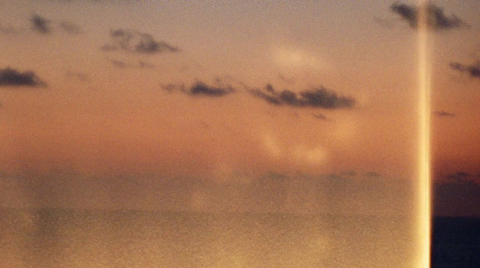 a plane flying over a body of water under a cloudy sky