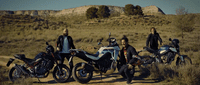 a group of people standing next to motorcycles on a dirt road