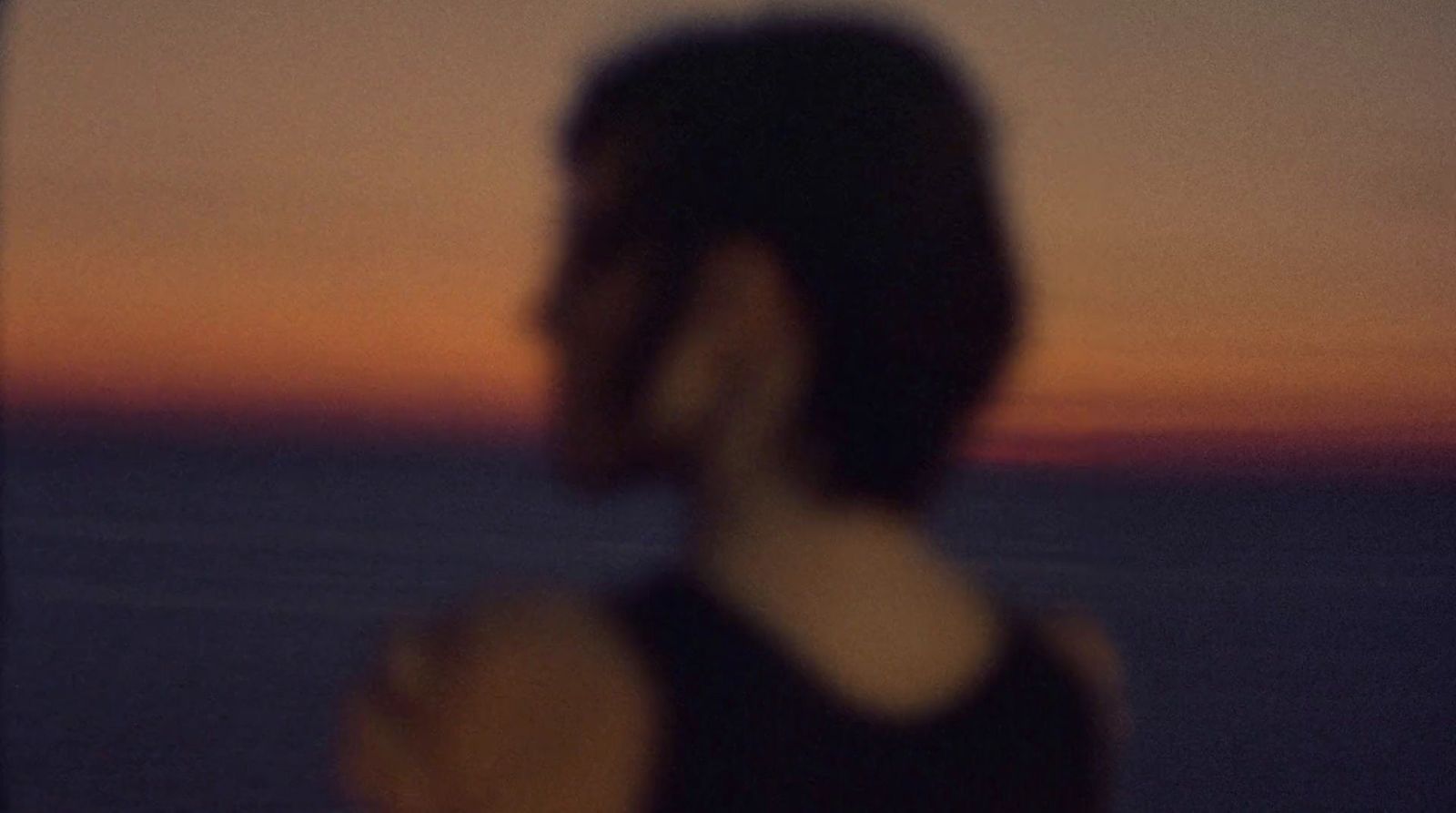 a blurry photo of a person standing in front of a sunset