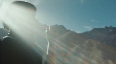 a man standing in front of a mountain under a blue sky