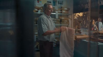 a man standing in front of a bakery holding a bag of bread