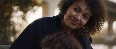 a woman with curly hair holding a small dog