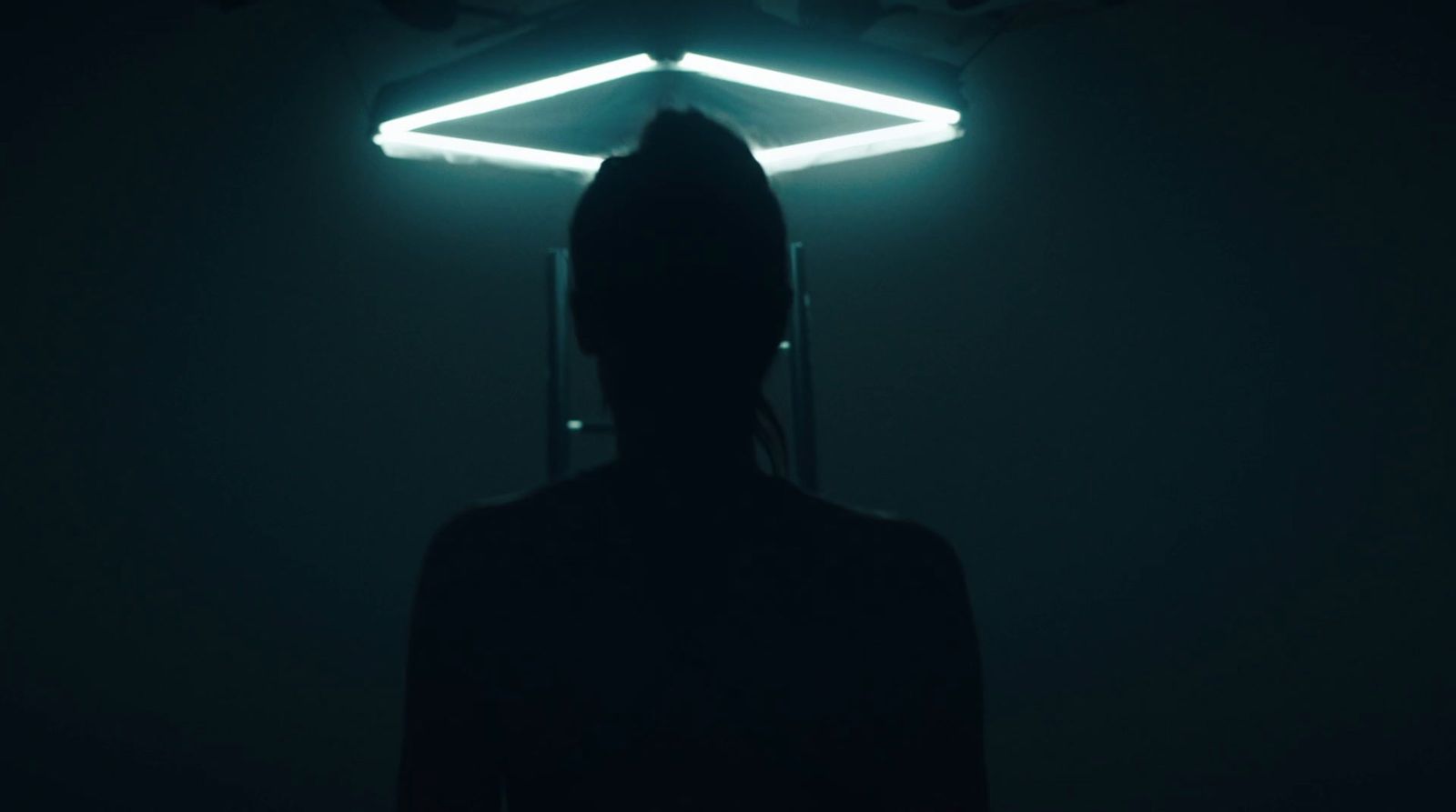 a person standing in a dark room with a neon light above their head