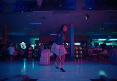 a girl is dancing in a bowling alley